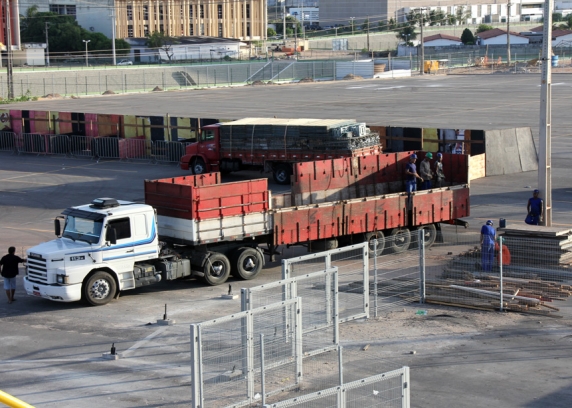 Operários da empresa montadora da estrutura metálica dos camarotes e arquibancadas descarregam material.