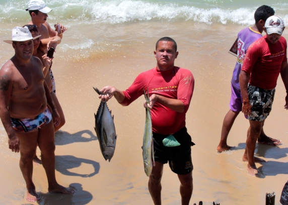 Cena comum de ver próximo aos guardas sóis da praia de Pipa, no largo de São Sebastião, quandos pescadores retornam de suas pescarias exibindo os peixes aos curiosos turistas.